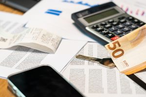 Documents administratifs, billets en euros, calculatrice et smartphone