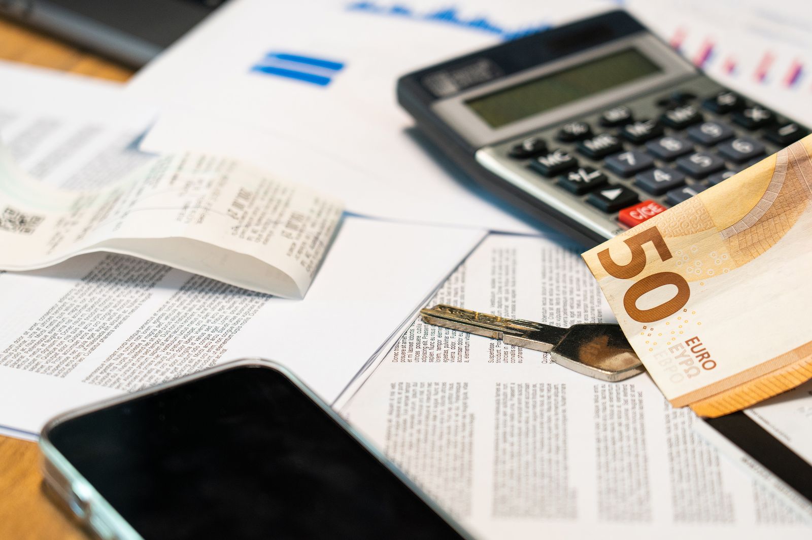 Documents administratifs, billets en euros, calculatrice et smartphone