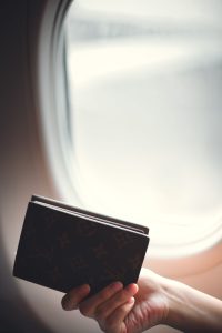 Passeport tenu près du hublot d’un avion