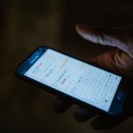 Main tenant un smartphone affichant une application de messagerie