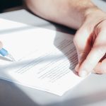 Deux personnes signant un document avec un stylo