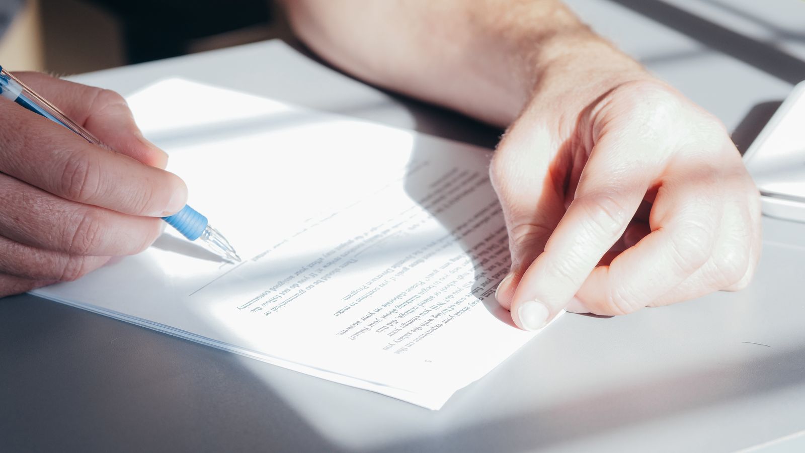 Deux personnes signant un document avec un stylo